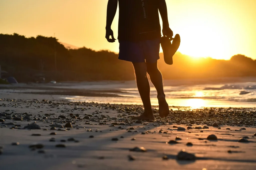 Vitamin D sunlight benefits for men walking on the beach at sunrise