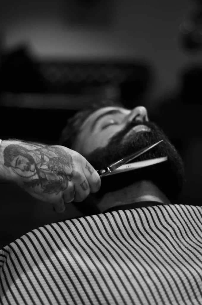 Man with a well-groomed beard receiving a hot towel treatment at the barbershop
