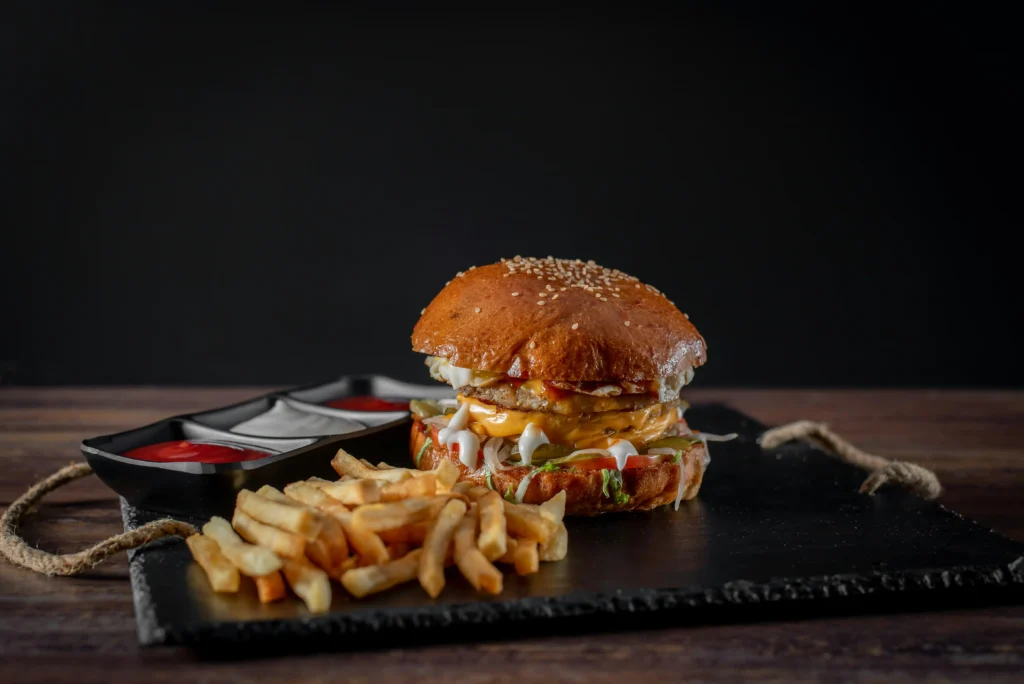 Fast food burger and fries on dark background, symbolizing unhealthy but tempting meal