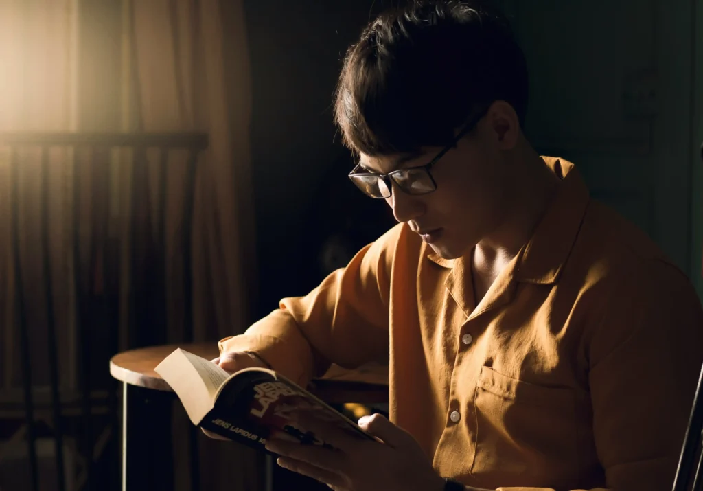 Sleep and recovery for men – man reading before bed during night routine
